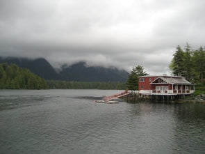 red house on the water with fog lifting 