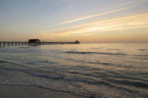 sun setting on the naples pier and gulf of mexico