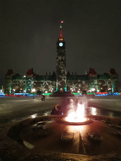 christmas lights on parliament hill with the eternal flame burning in the forefront
