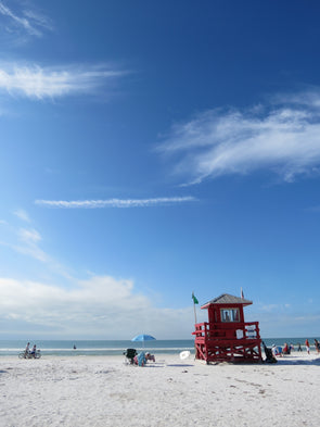 bright blue skies, whispy clouds and white clouds with red lifeguard stand on siesta key, florida